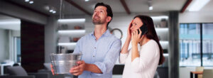 Couple catching water from a leak while calling a plumber.