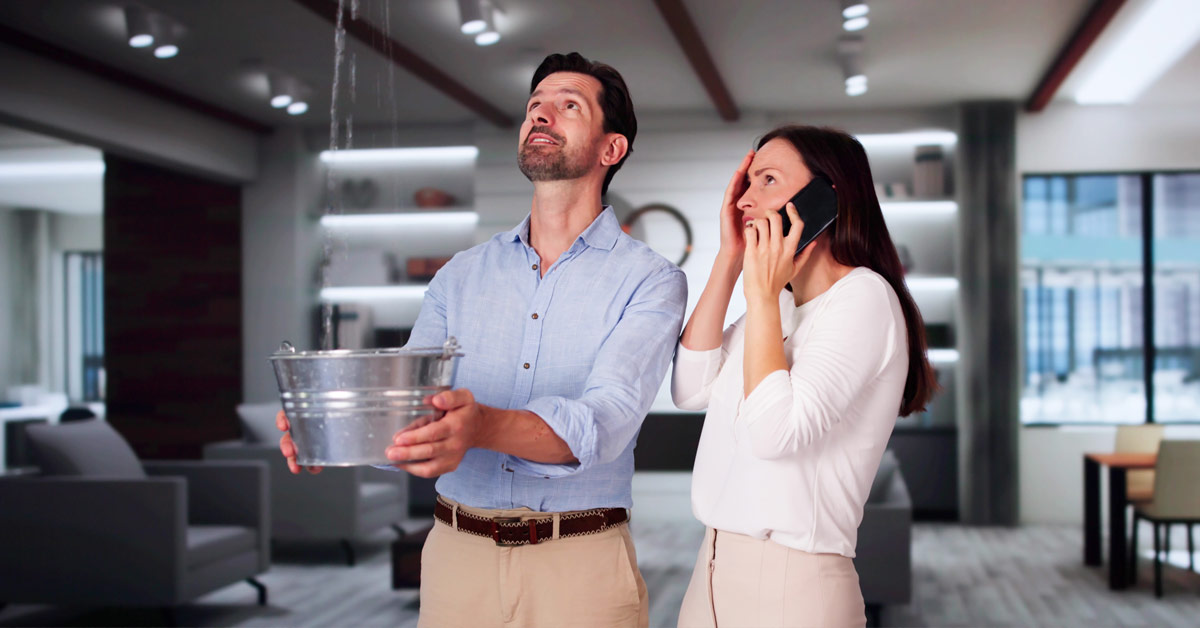 Couple catching water from a leak while calling a plumber.