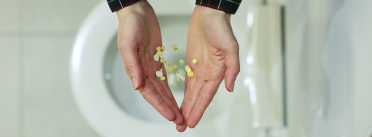 Hands dropping medication in the toilet.